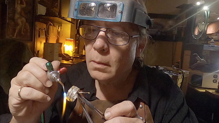 Todd Alan using a torch to make a ring by hand. Todd handmakes all his braided wedding rings. Artist Todd Alan making a ring.