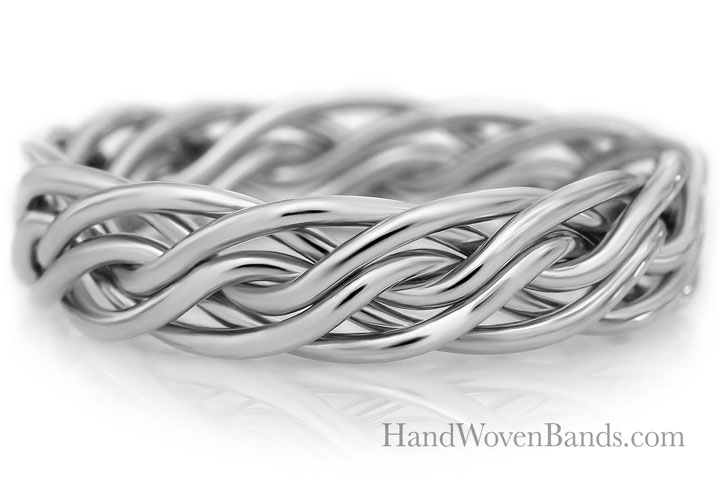 Gold-plated handwoven band with intricate looping design displayed on a reflective surface.