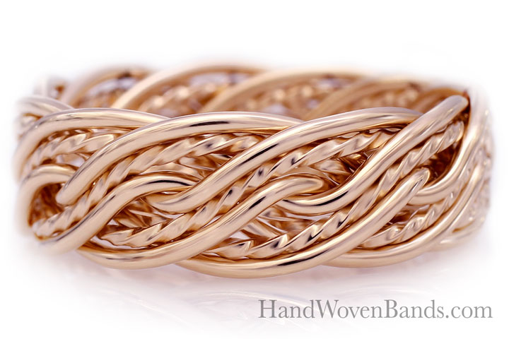 A close-up image of a ten-strand braided gold ring reflecting on a white surface, with the watermark "handwovenbands.com" visible.