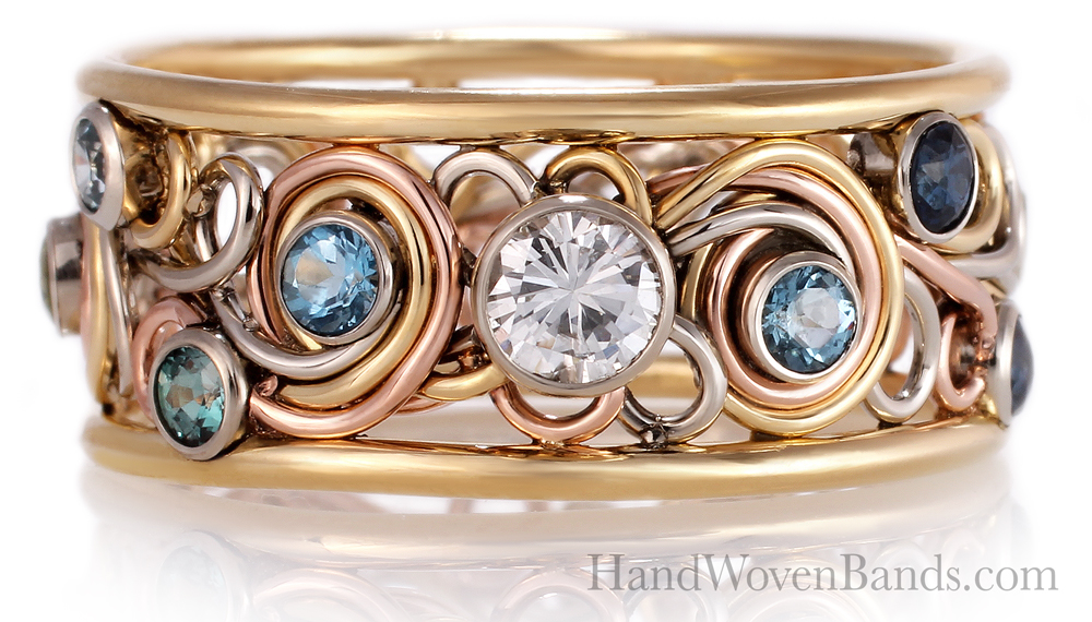 Unique gold and rose gold handwoven band ring featuring a central diamond flanked by smaller blue gemstones, on a reflective surface.