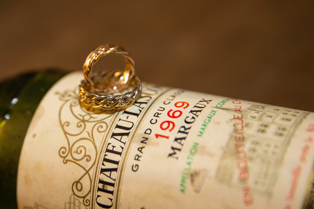 Two interlocked gold Sx Strand rings on a 1989 château margaux wine bottle label.