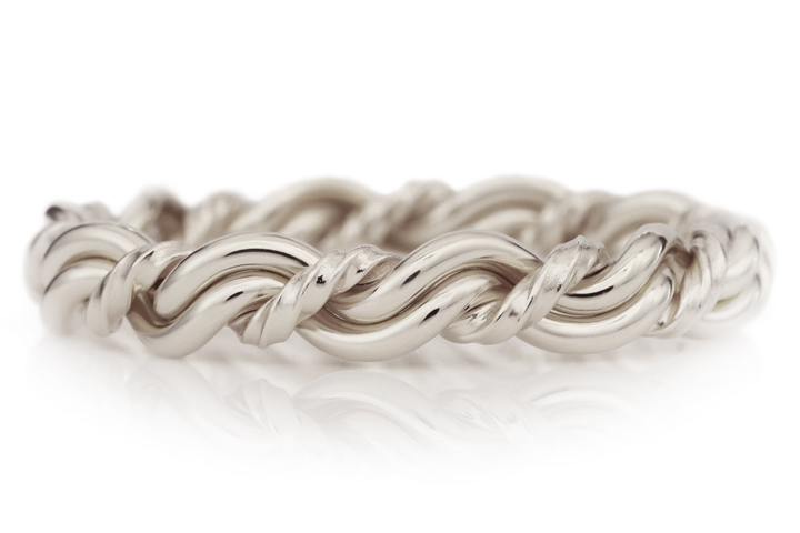 A silver twisted rope bracelet, resembling a cord of three strands wedding ring, isolated on a white background.