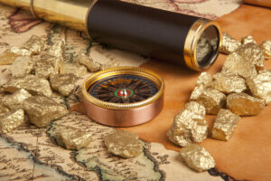 A brass compass and a telescope beside gold investments on an antique map.