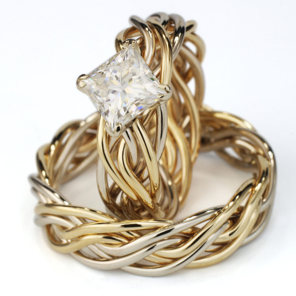 A gold and silver twisted open weave ring with a large square-cut diamond set atop, displayed on a white background.