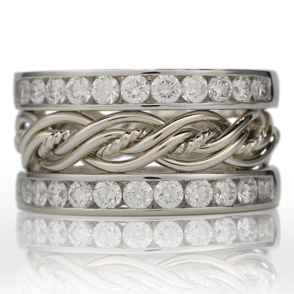 Three stacked unique diamond wedding rings; two feature all-around set diamonds and one has a braided metal design.