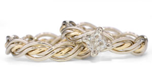 Gold and silver interlinked chain bracelet with a central diamond in a prong setting on a white background.