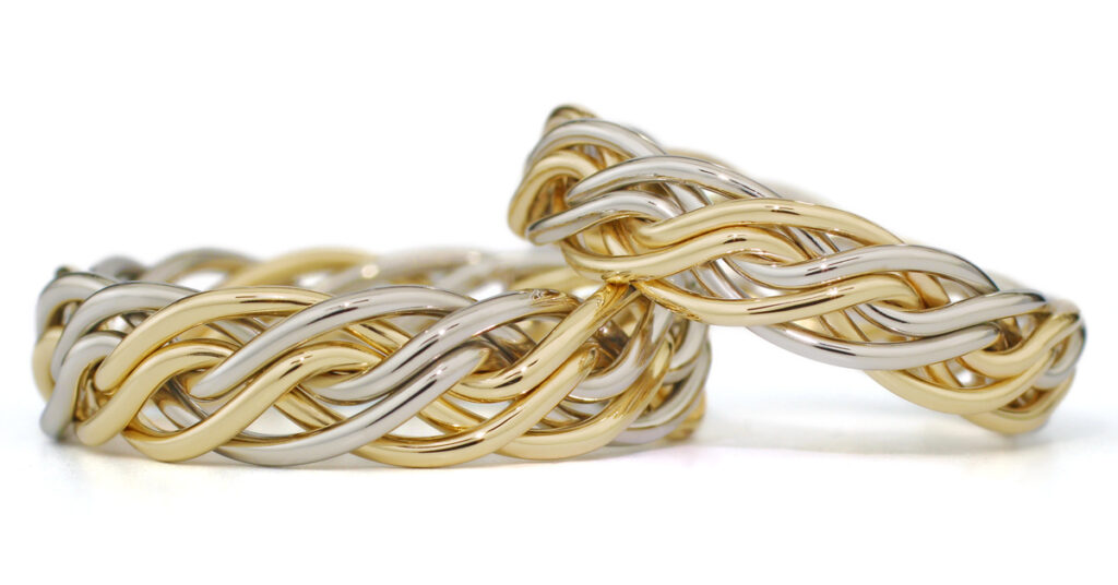 Two intertwined gold and silver wedding rings on a white background.