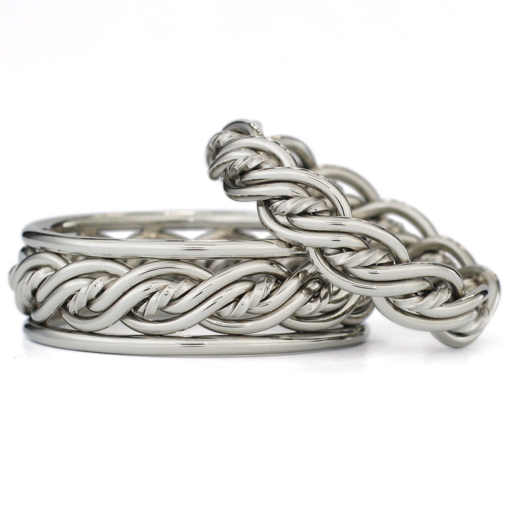 Two intertwined silver braided chain bracelets on a white background.
