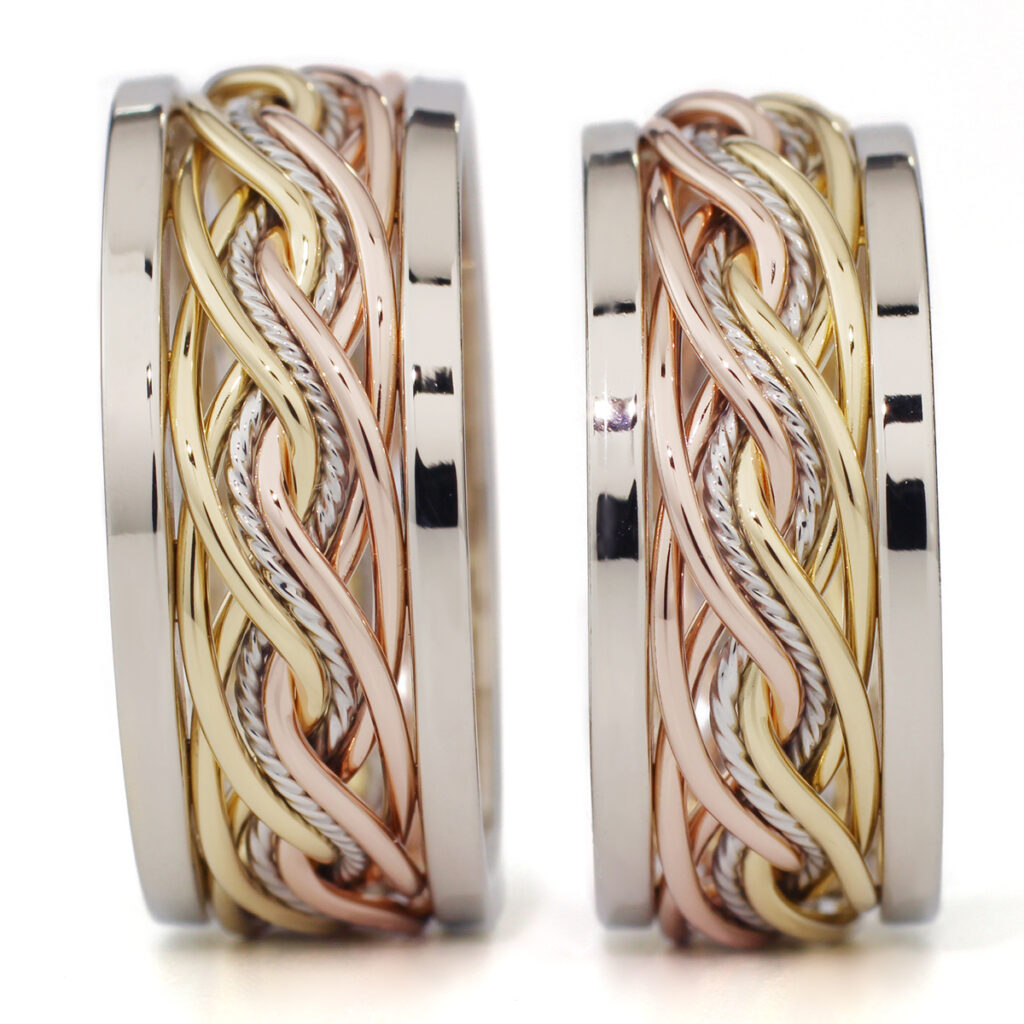 Two intricately designed braided wedding rings in silver and gold tones with a woven pattern, displayed against a white background.
