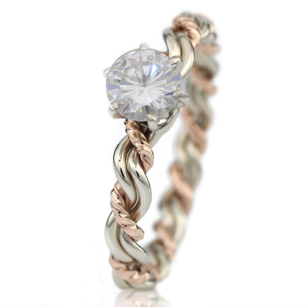 An elegant two-tone twisted engagement ring featuring a prominent solitaire diamond, set against a white background, embodies the essence of unique engagement rings.