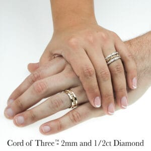 Two hands show braided diamond gold Cord of Three rings, handwoven with unique artistry by Todd Alan.