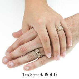 Close-up of two hands wearing matching handwoven gold wedding rings with braided design by Todd Alan.