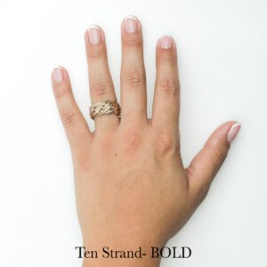 Handwoven gold braided ring with unique open weave design on manicured hand, artisan-crafted by Todd Alan.