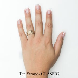 Gold braided handwoven ring on manicured hand, unique wedding or engagement ring by Todd Alan. Ten Strand Classic.