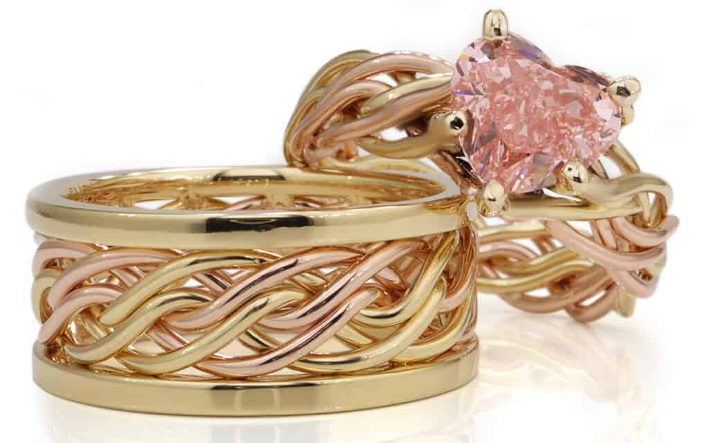 Handwoven gold and rose gold braided rings, one with a heart-shaped pink gemstone. Unique design by Todd Alan.