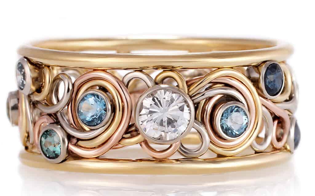 Unique gold braided ring with central white gemstone, blue and aqua stones, handcrafted by Todd Alan.